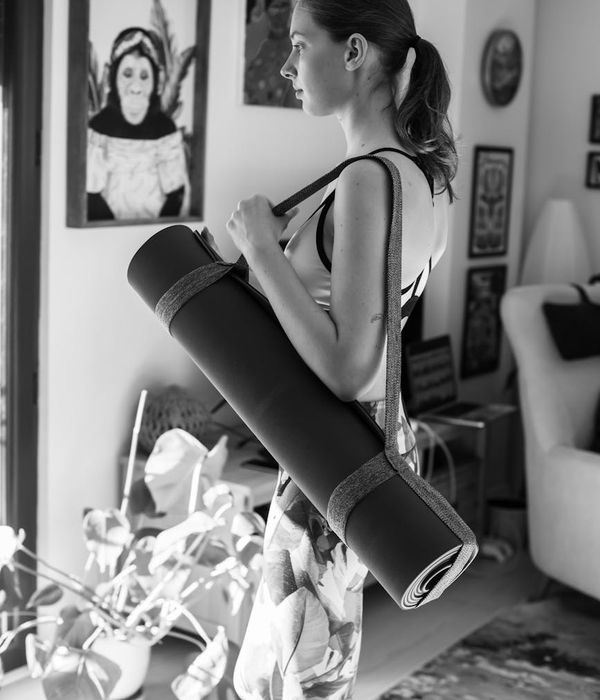 Woman in a serene yoga pose in a minimalist room with gold light.